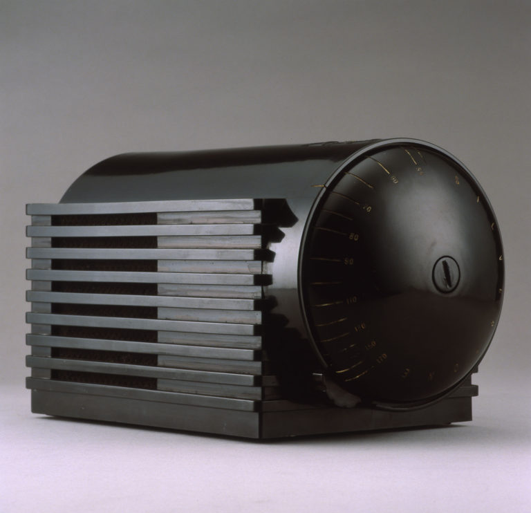 Black plastic radio with cylindrical body and rectangular base. One domed end of the body is the control dial.