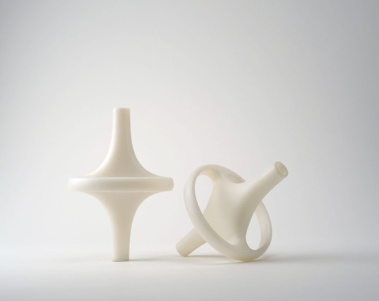 Deux vases de plastique blanc, chacun formé d’un long tube évasé au centre pour être entouré d’un large anneau.