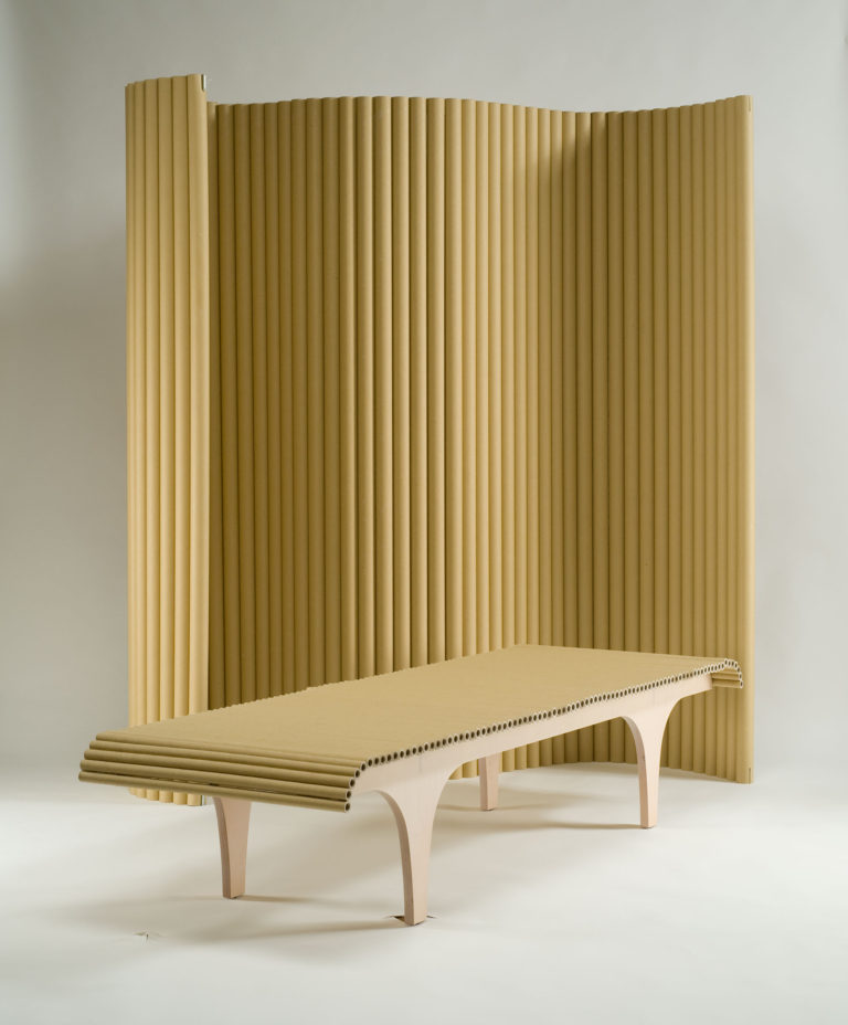 Tall adjustable screen made of vertical cardboard tubes and wood-framed bench with cardboard-tube seat.