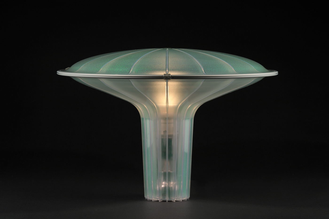 Translucent green plastic table lamp with conical base rising up and flaring outward with a domed top.