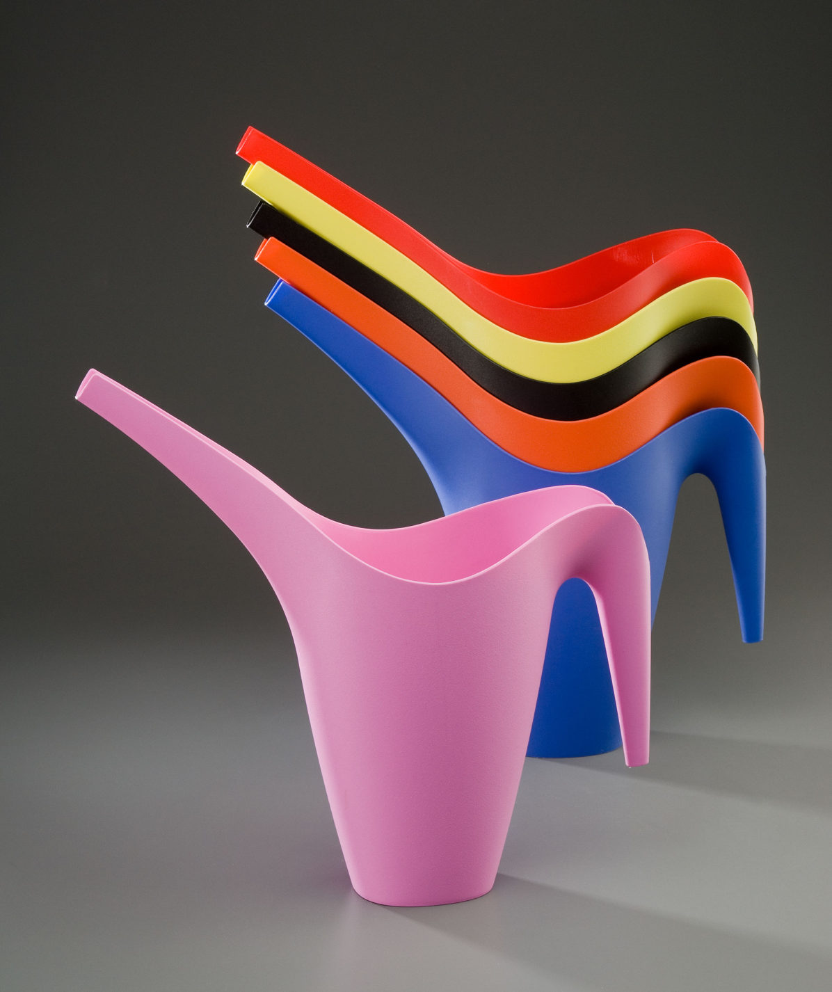 Six watering cans with long swooping handles and spouts. Each is a different color: pink, blue, orange, yellow, black, and red.