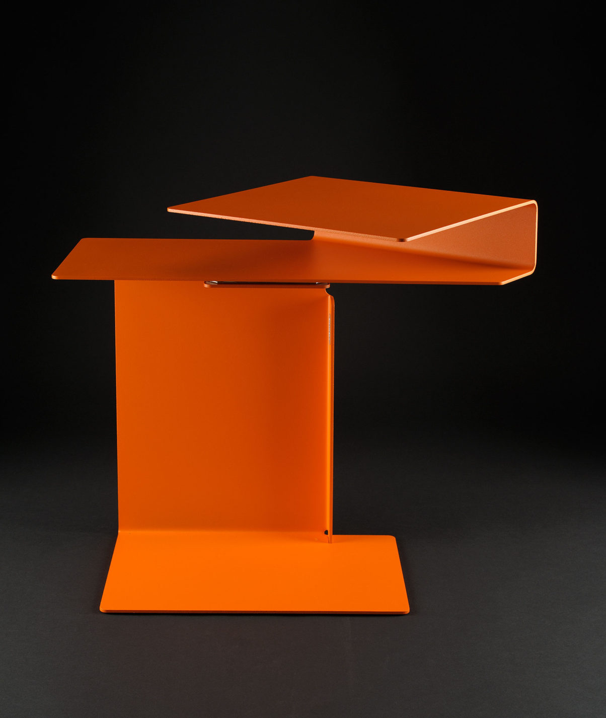 Petite table composée d’une feuille de métal orange.