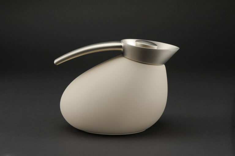 Bulbous beige jug with brushed-metal spout, lid, and handle, similar to the form of a classic restaurant coffeepot but canted forward.