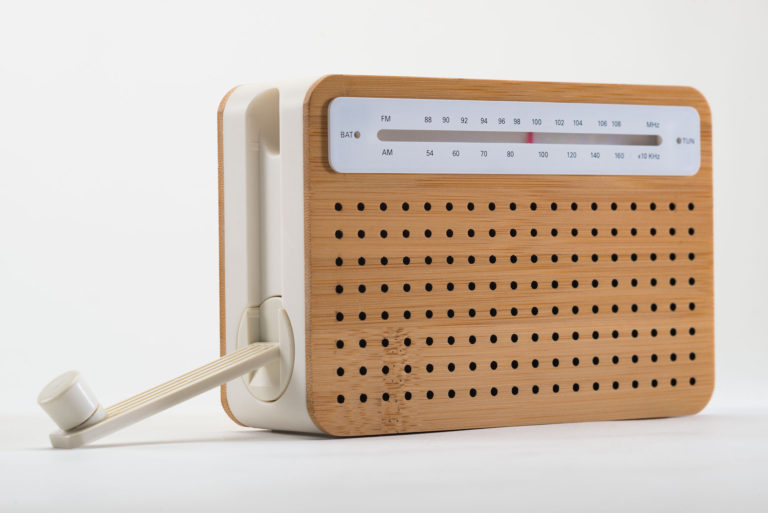 Radio portative rectangulaire à cadre de plastique blanc avec revêtement de bambou perforé.