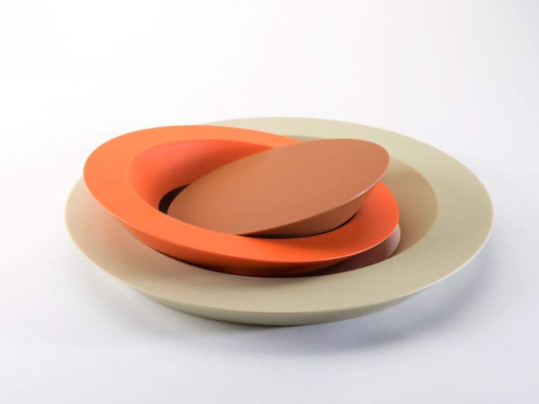Assiette à gâteau décomposée faite de trois cercles concentriques : un anneau extérieur blanc cassé, un anneau intermédiaire orange et un centre chocolat.