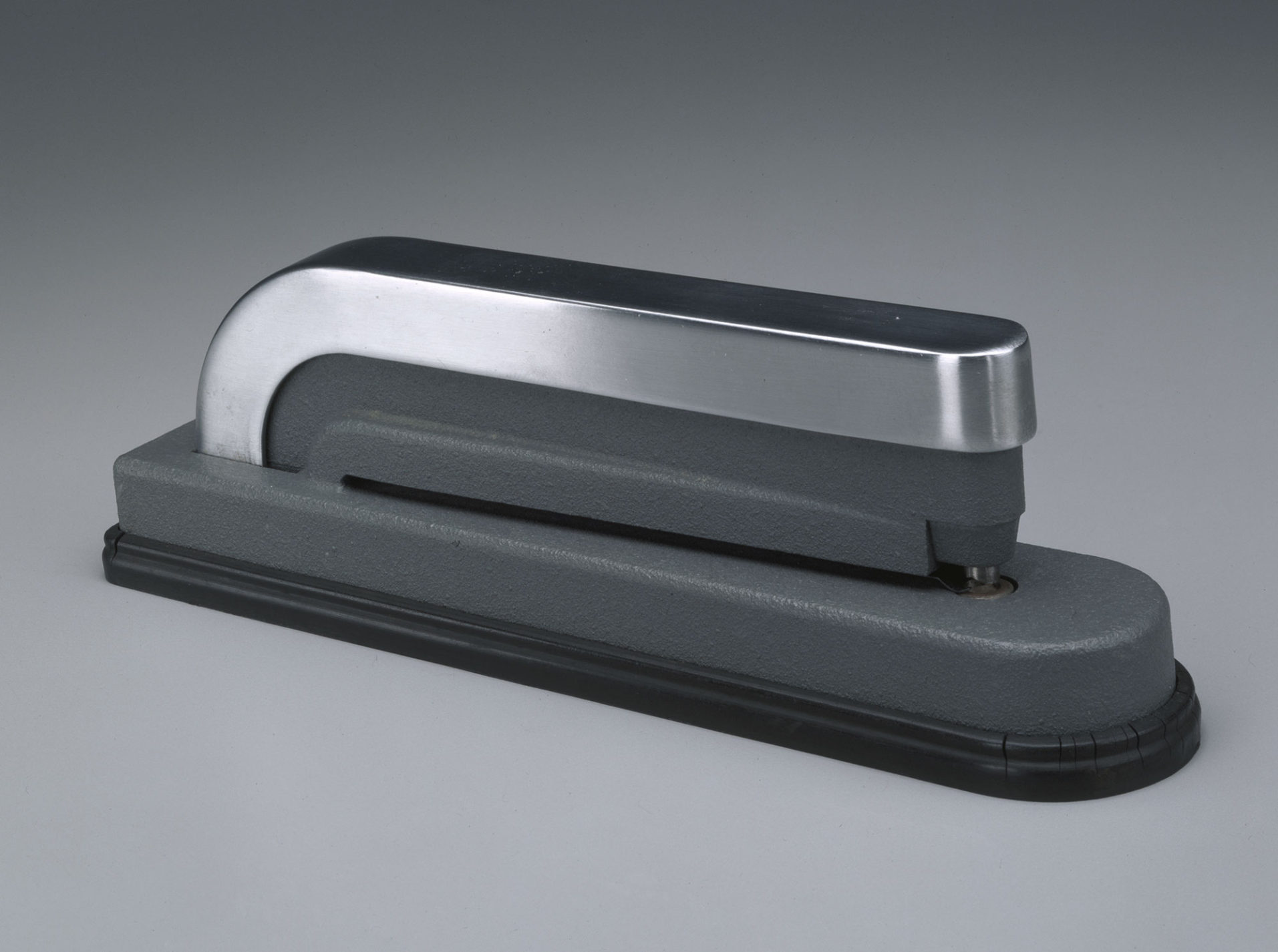 Hole punch in grey and polished metal that resembles a stapler with rounded corners.