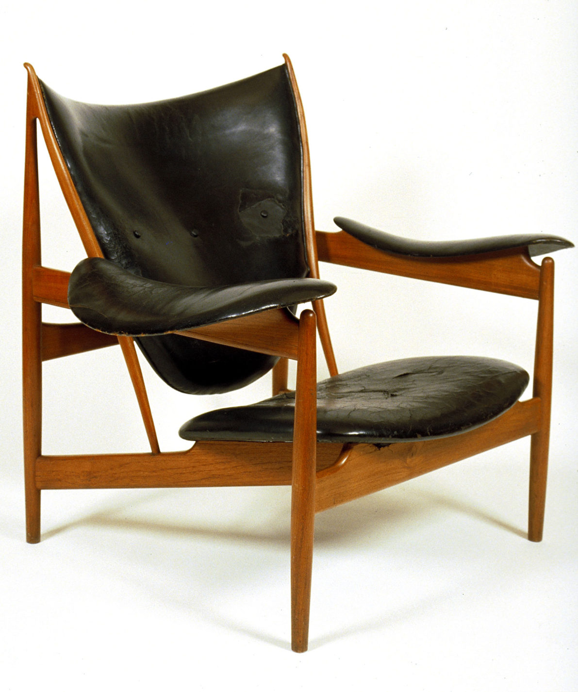 Armchair with an angular wooden frame and swooping leather cushions for the seat, back and arms.