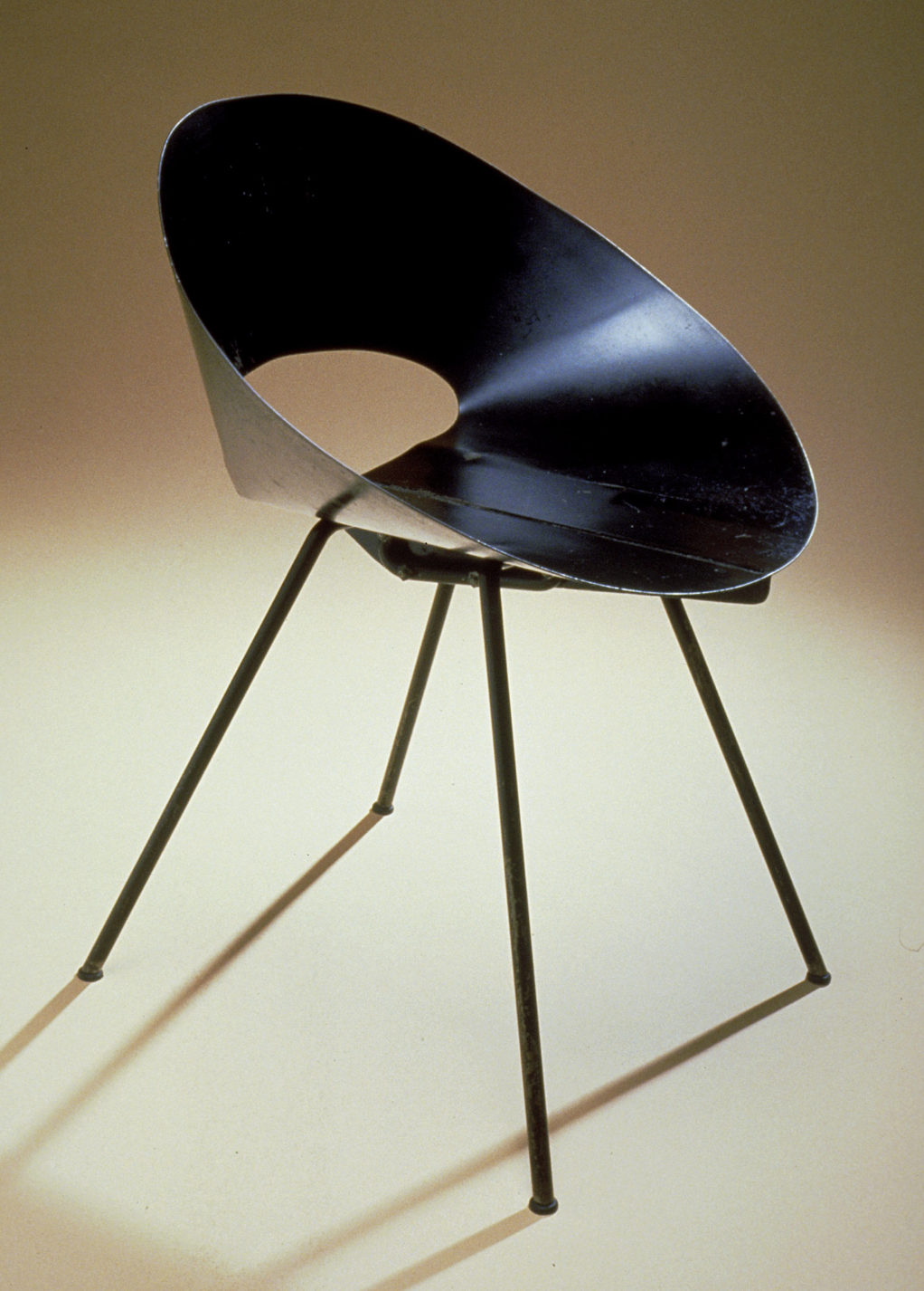 Chaise avec assise et dossier en tôle d’acier noir de forme conique et aux quatre pattes inclinées.