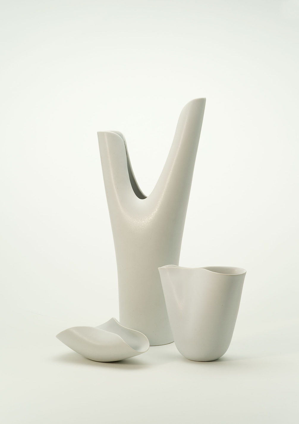 Deux vases de forme et de taille différentes, et un bol de porcelaine blanc cassé.