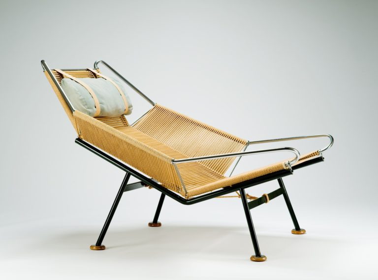 Chaise semi-inclinée à quatre pattes avec assise, dossier et accoudoirs faits de corde enroulée autour d’un cadre de métal noir et chromé.