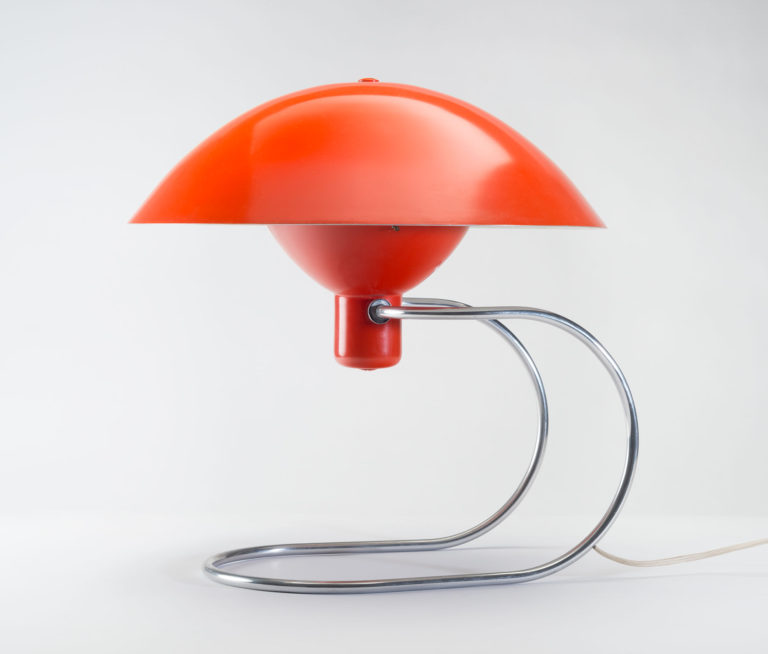 Lamp with a bright red dome shade and curved metal frame base.