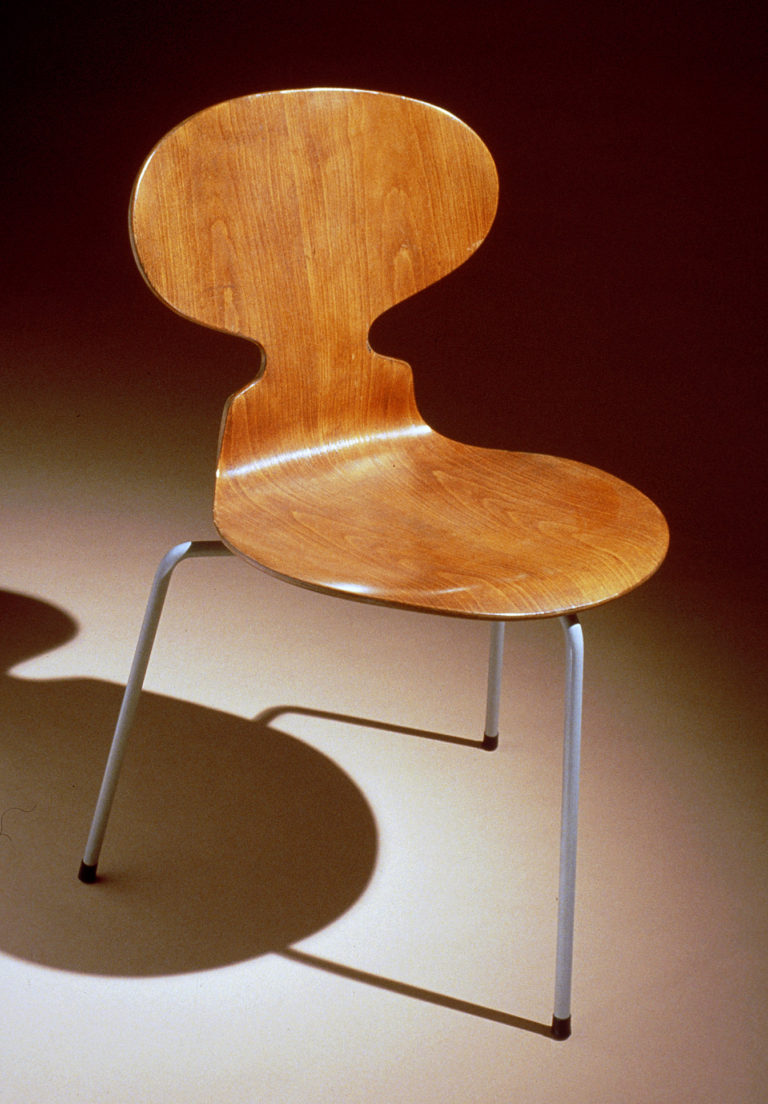 Chair with a single piece of plywood bent to form the oval back and round seat supported by three steel tubular legs.
