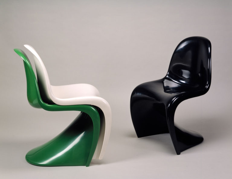Three curvy plastic stacking chairs in different colors: black, white, and green.