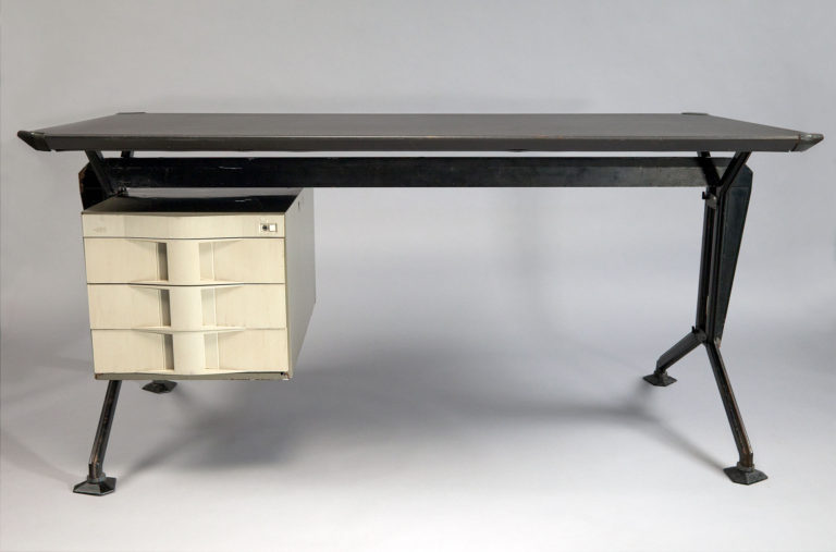 Desk with rectangular plywood top supported by an angular steel frame with a white drawer unit suspended on the left side.