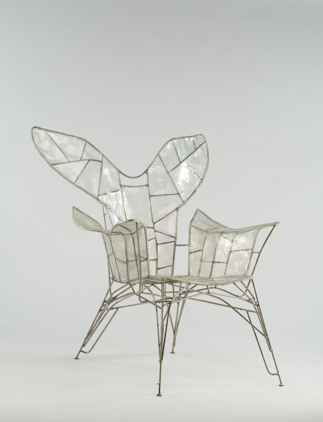 Wire-framed armchair covered in transparent plastic and resembling insect wings.