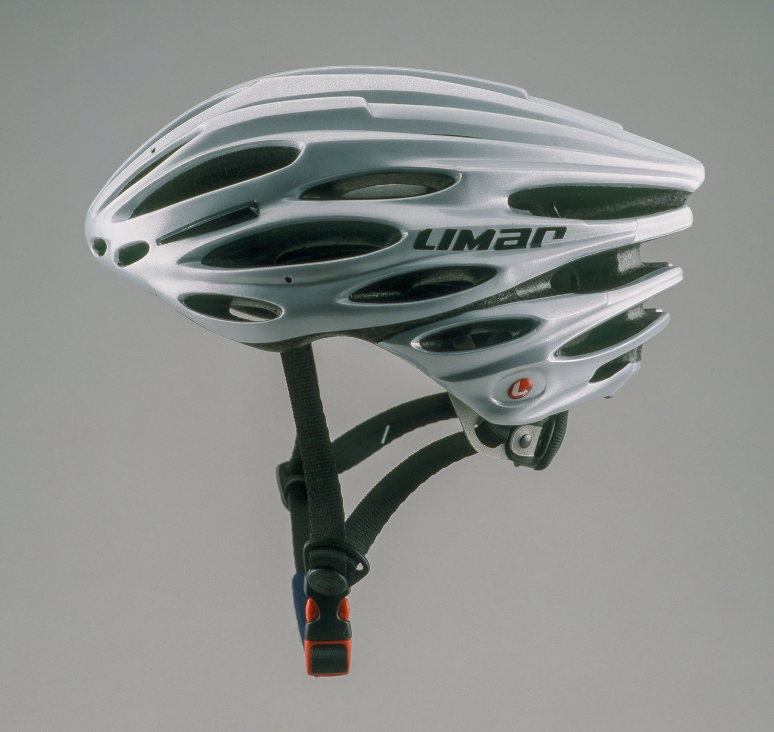 Silver-colored bicycle helmet in a sweeping teardrop shape with numerous ventilation openings and and black brim.
