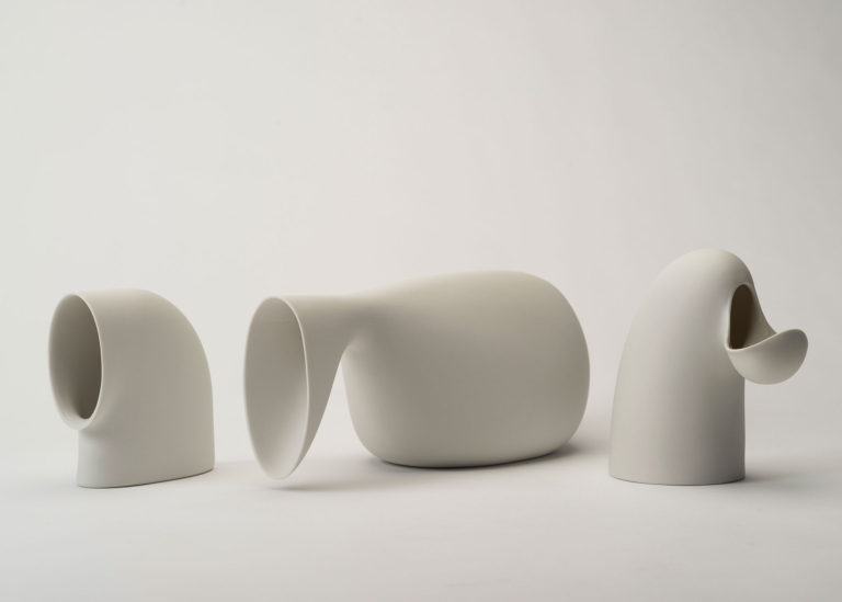 Three vessels in surprising, curving shapes, made of matte white porcelain.