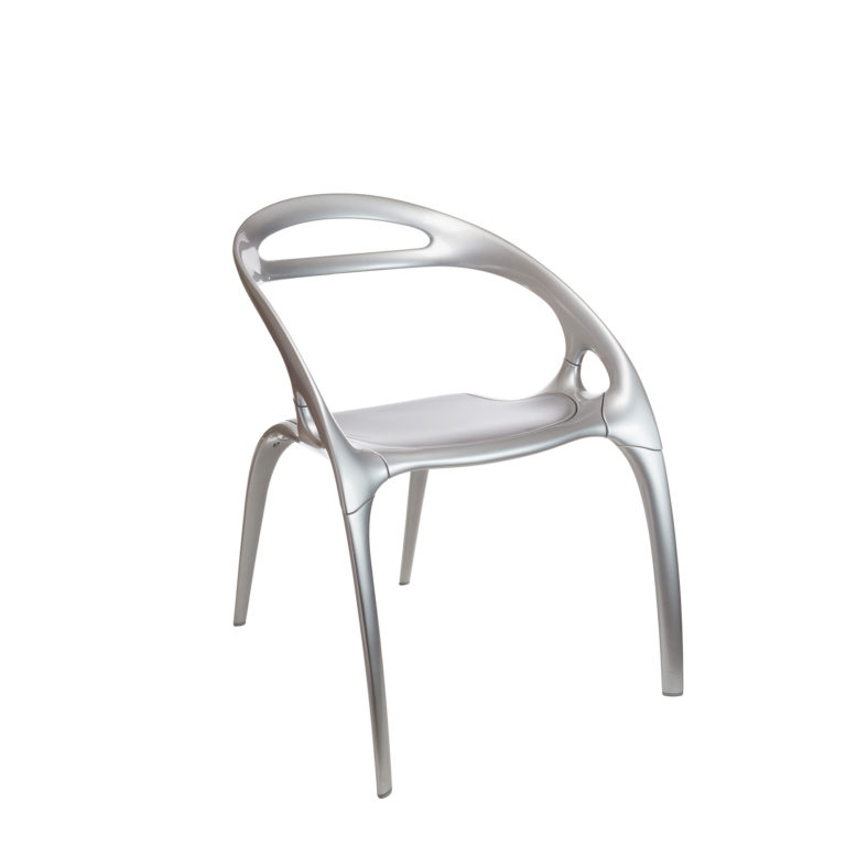 Metallic chair. Back and arms are made of a single swoop of metal above the seat and four slender swooping legs below.