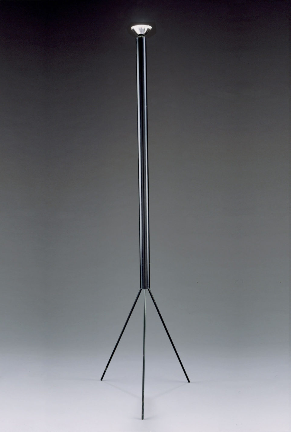 Black floor lamp with a tripod base and long cylindrical stem with a bare halogen bulb at the top.