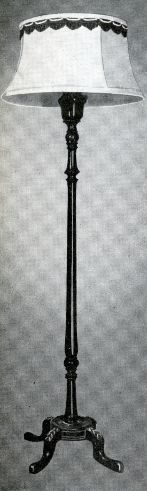 Lampe à pied munie d’un abat-jour décoratif, d’un pied fabriqué au tour, et d’une base composée de quatre pattes ornées.